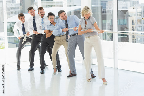 Group of business people pulling rope in office