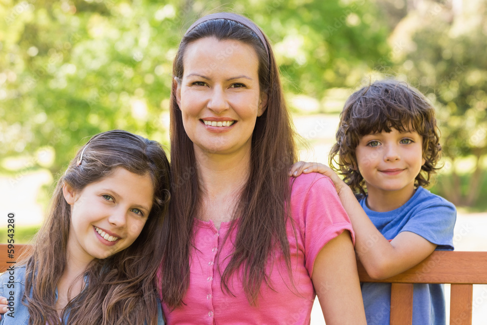 Smiling woman with kids sitting on park bench Smiling woman with kids sitting on park bench