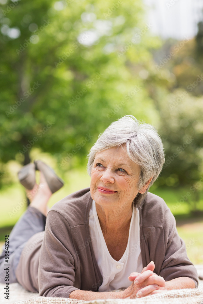 Thoughtful senior woman lying at park Thoughtful senior woman lying at park