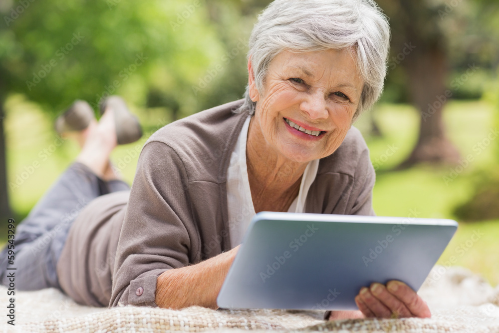 Smiling senior woman using digital tablet at park Smiling senior woman using digital tablet at park
