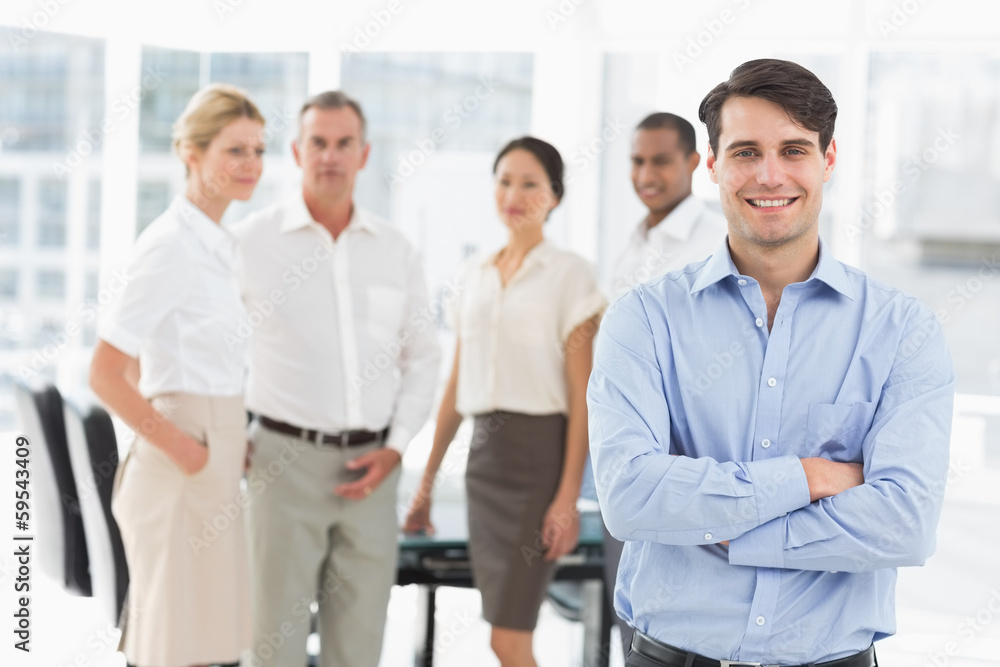 Happy businessman standing with team behind him Happy businessman standing with team behind him
