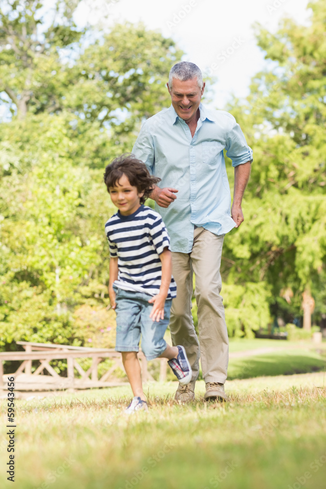 Grandfather and son running on grass in park Grandfather and son running on grass in park