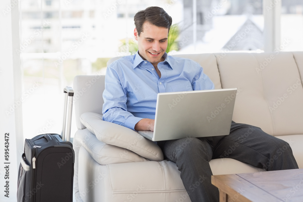 Travelling businessman using laptop sitting on the couch Travelling businessman using laptop sitting on the couch
