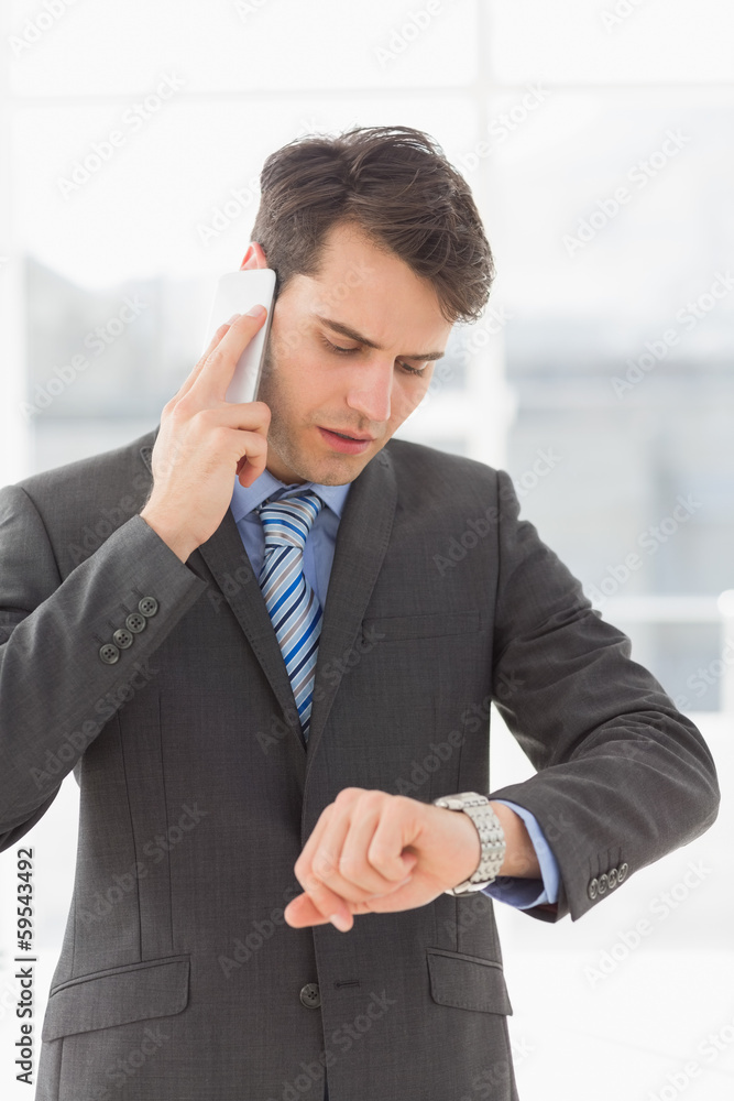 Serious businessman checking the time while on the phone