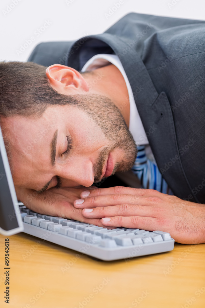 Businessman resting with head over keyboard at desk Businessman resting with head over keyboard at desk