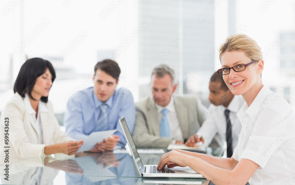 Businesswoman using her laptop during a meeting looking at camer Businesswoman using her laptop during a meeting looking at camer