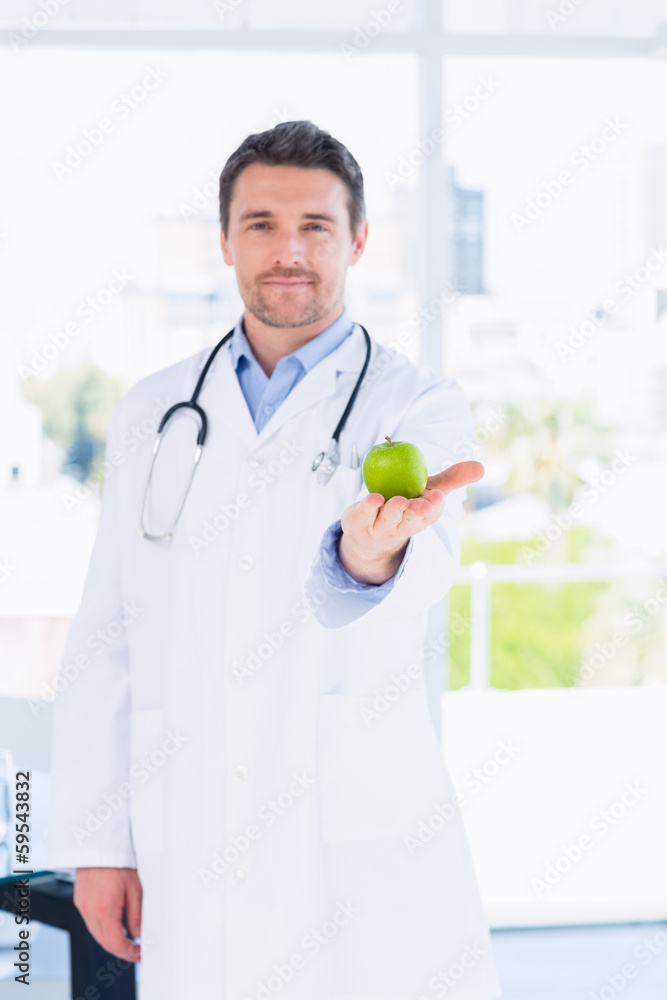 Portrait of a smiling male doctor holding an apple Portrait of a smiling male doctor holding an apple