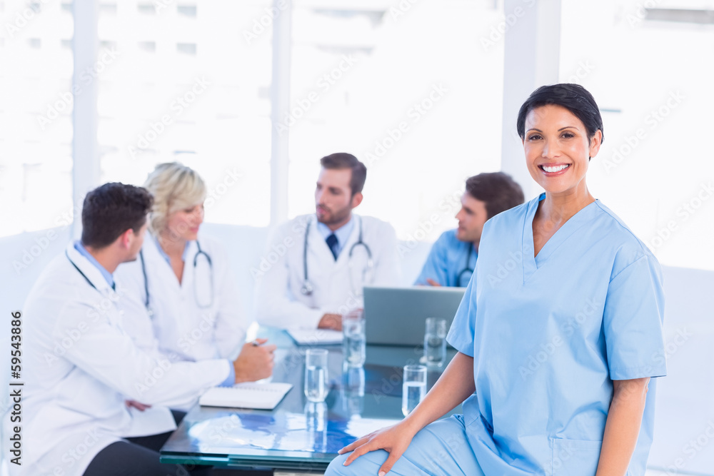 Smiling female surgeon with colleagues in meeting