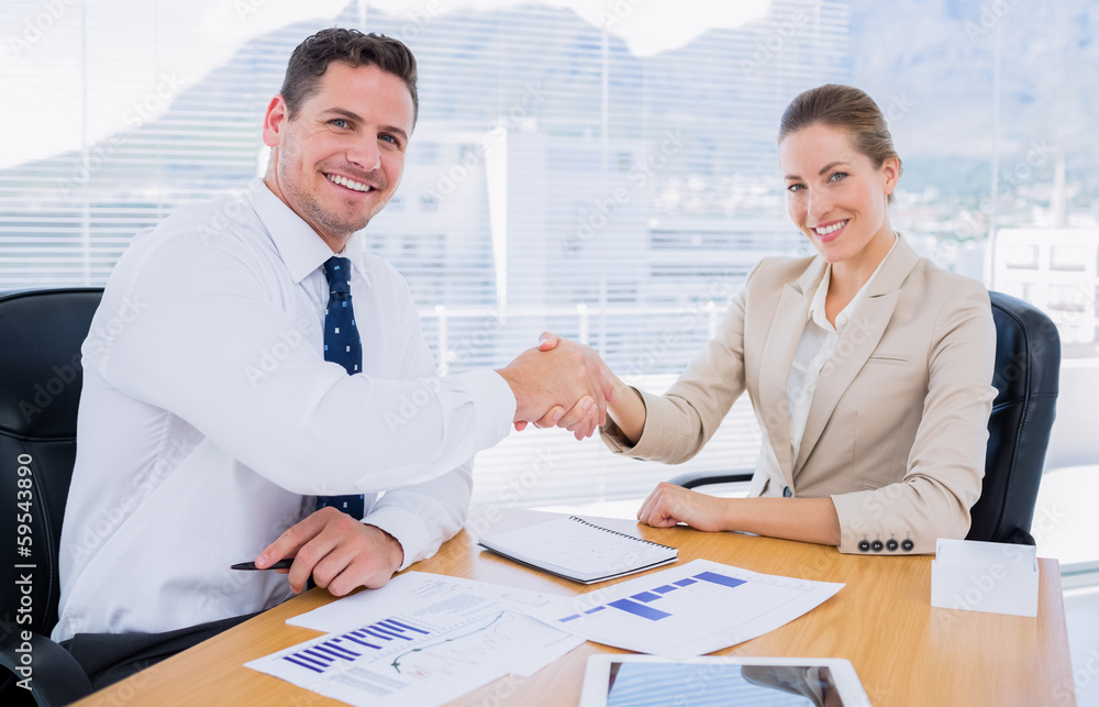 Smartly dressed colleagues shaking hands in a business meeting Smartly dressed colleagues shaking hands in a business meeting