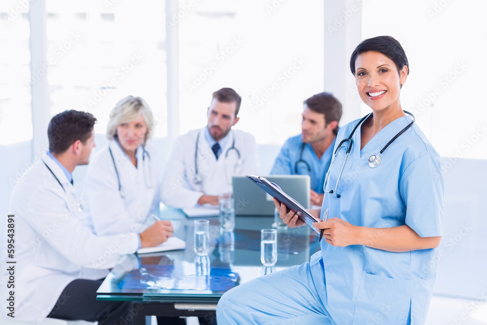 Female surgeon holding reports with colleagues in meeting Female surgeon holding reports with colleagues in meeting