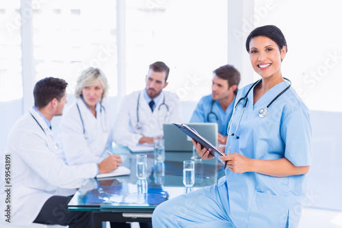Female surgeon holding reports with colleagues in meeting