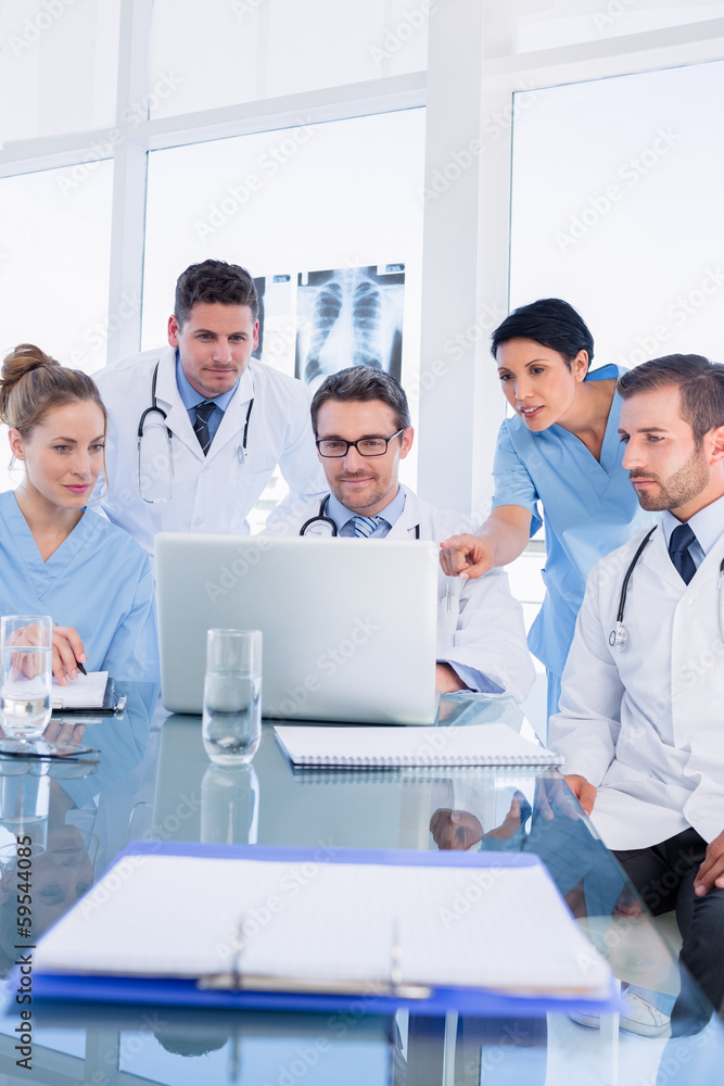 Concentrated medical team using laptop together Concentrated medical team using laptop together