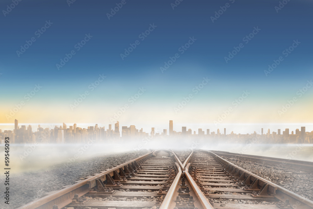 Railway tracks leading to city on the horizon