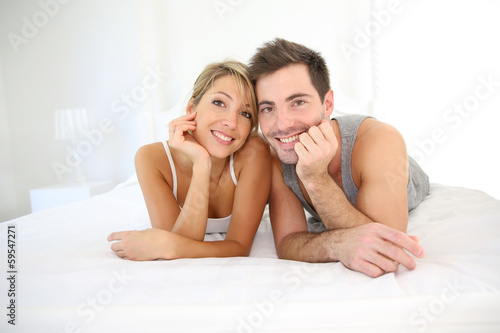 Portrait of cheerful young couple laid on bed