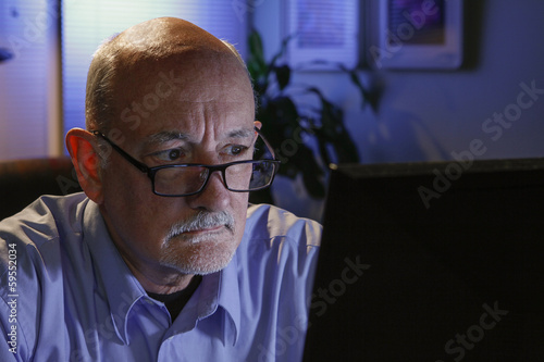 Close up of serious older man reading off his computer