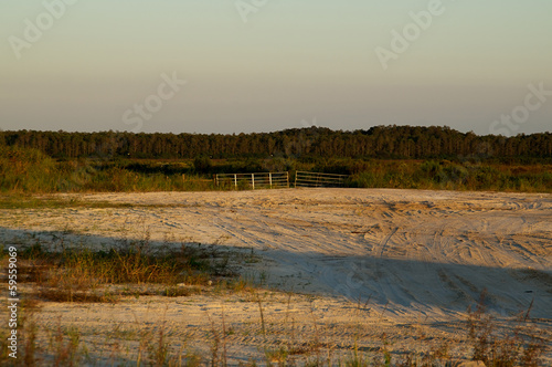 end of dirt road blocked by gate at sunset