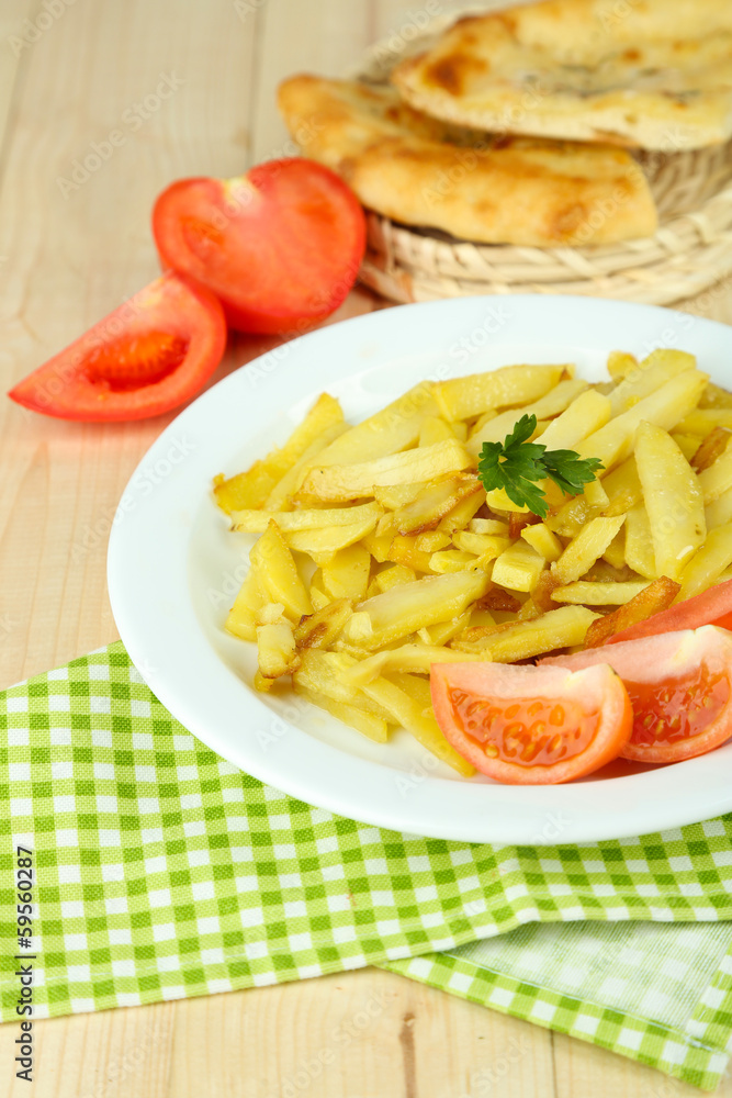 Fried potatoes on plate on wooden table close-up Fried potatoes on plate on wooden table close-up
