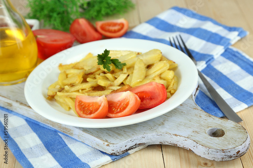 Ruddy fried potatoes on plate on wooden table close-up