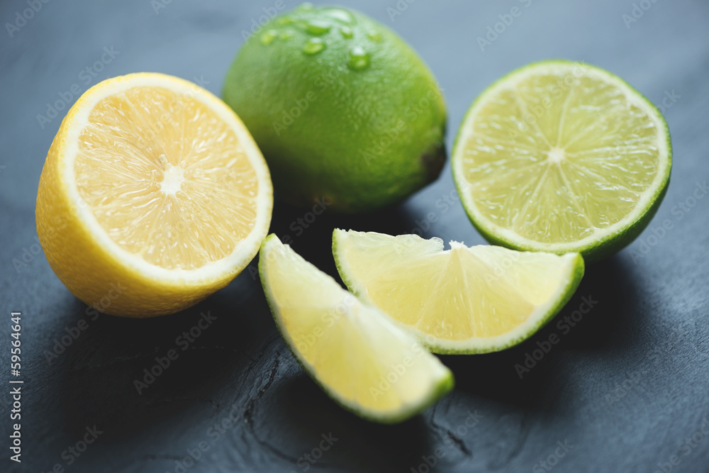 Still life of sliced lemons and limes over black wooden surface Still life of sliced lemons and limes over black wooden surface