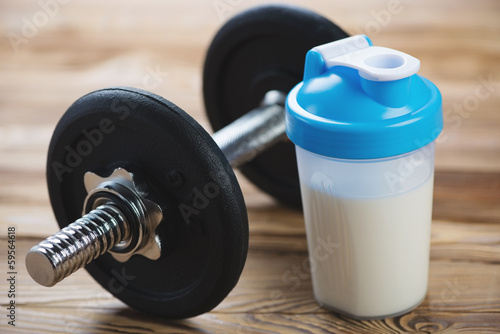 Fototapeta Naklejka Na Ścianę i Meble -  Close-up of a dumbbell and a protein shake on a wooden surface