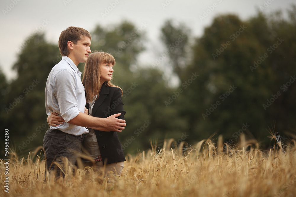 young man and woman walking in a field of wheat young man and woman walking in a field of wheat