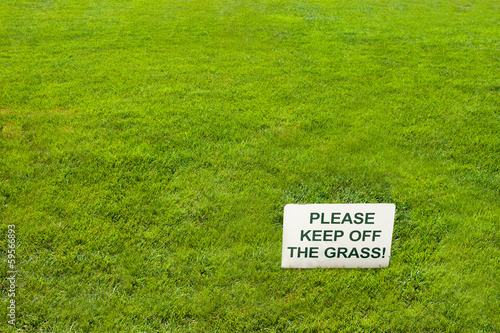 White Please keep off the grass sign on green grass. photo