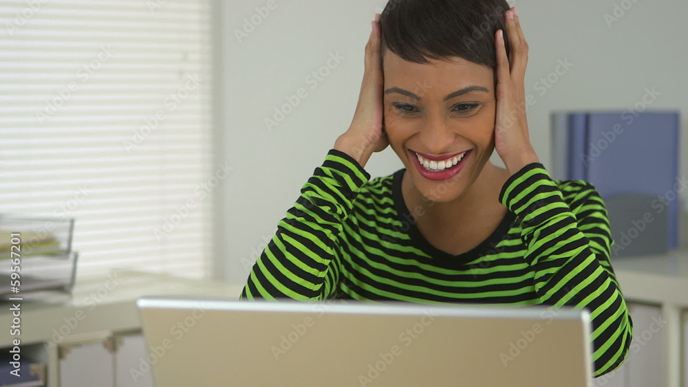 Smiling African American business woman celebrating in office Smiling African American business woman celebrating in office