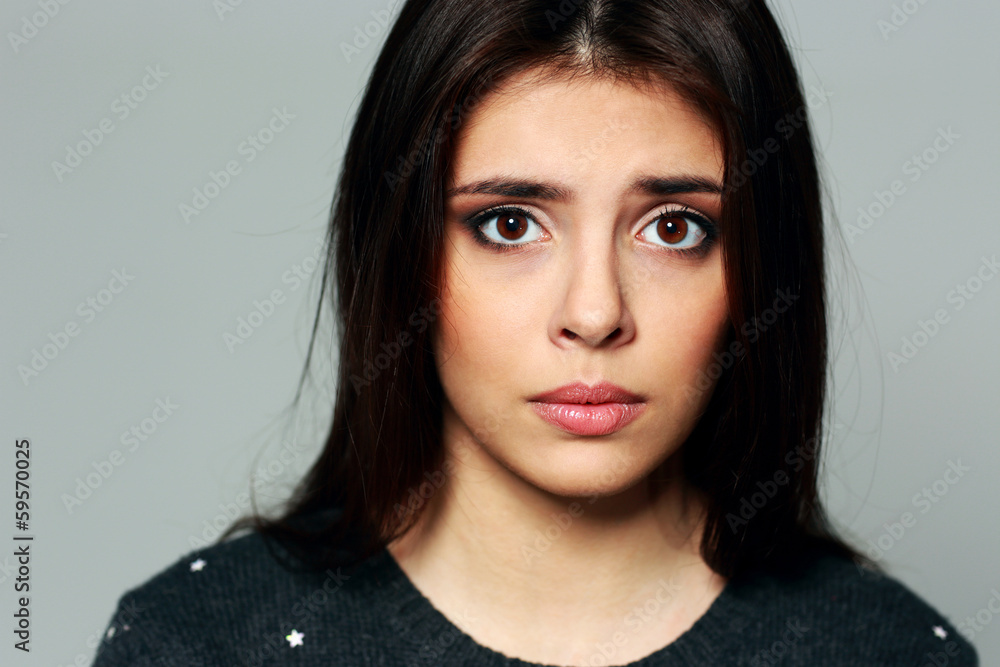 Closeup portrait of a young sad woman on gray background Closeup portrait of a young sad woman on gray background