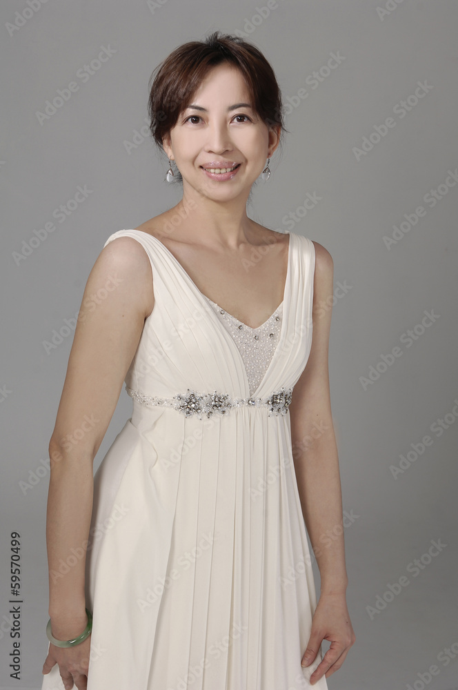beautiful smiling woman in a white wedding dress on a gray