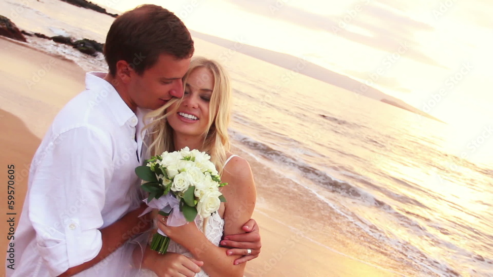 Newly married couple on tropical beach after sunset wedding
