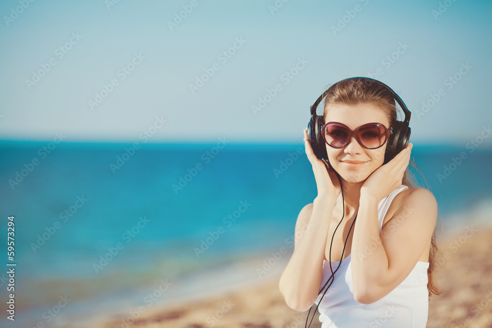 Portrait of a beautiful woman on the beach listening to music