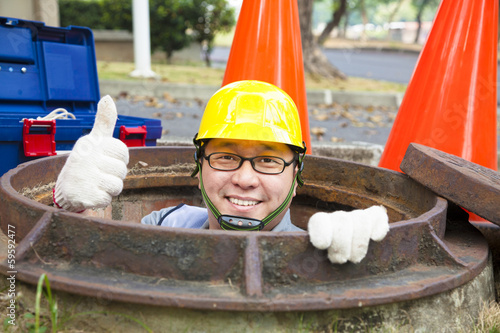 sewerage worker in the manhole with thumb up photo