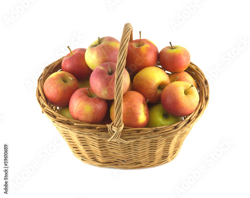 Brown wicker basket full of ripe apples isolated closeup