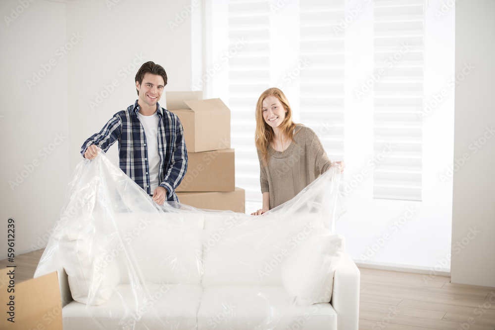 smiling couple unpacking sofa in new home smiling couple unpacking sofa in new home