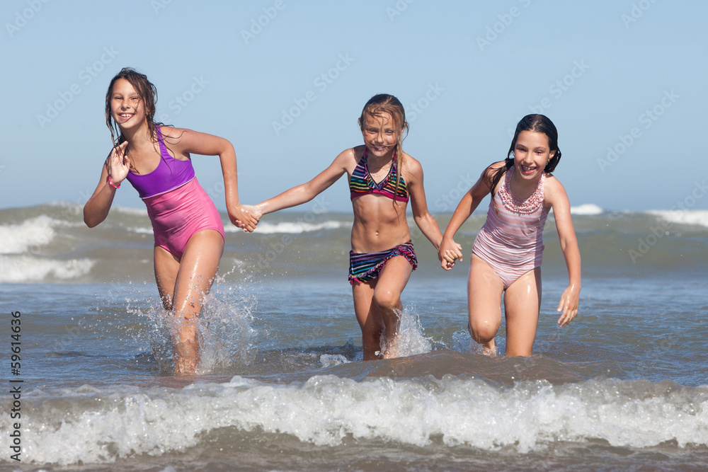three happy girls running out of ocean