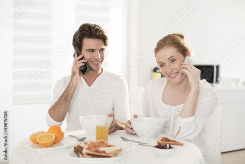 young couple takes breakfast in kitchen and communicates at phon