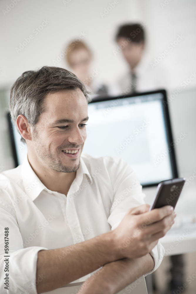 portrait of a businessman watching his smartphone at office