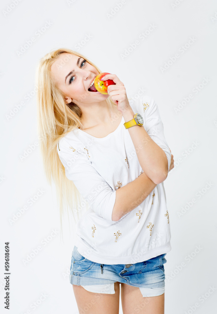 Young, cheerful girl biting an apple, isolated on white backgrou Young, cheerful girl biting an apple, isolated on white backgrou