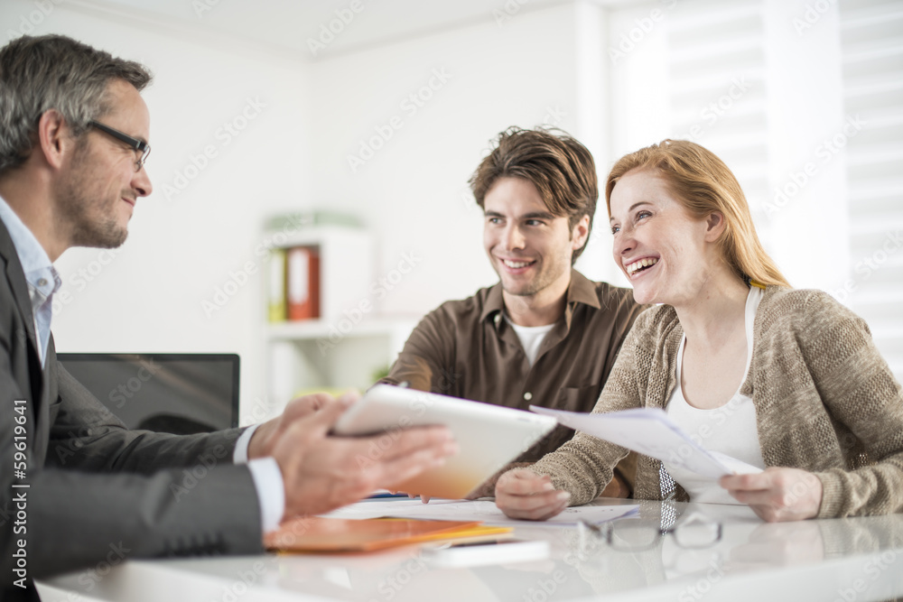 real-estate agent shows a build project on a digital tablet to a real-estate agent shows a build project on a digital tablet to a