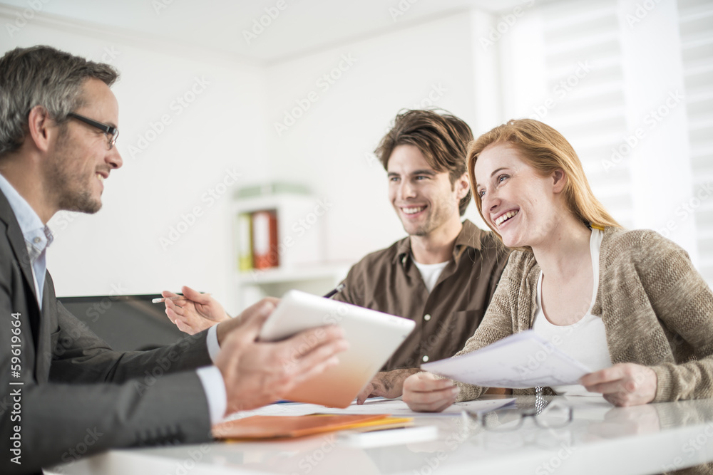 real-estate agent shows a build project on a digital tablet to a real-estate agent shows a build project on a digital tablet to a