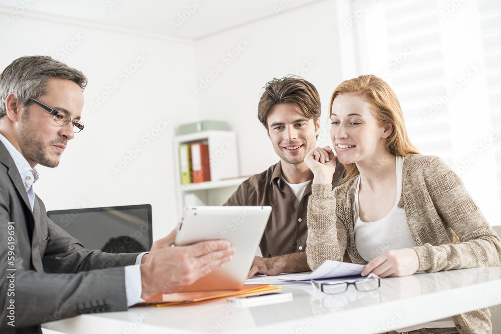 real-estate agent shows a build project on a digital tablet to a real-estate agent shows a build project on a digital tablet to a