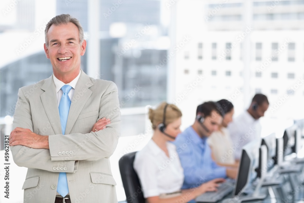 Happy businessman with executives using computers in office Happy businessman with executives using computers in office