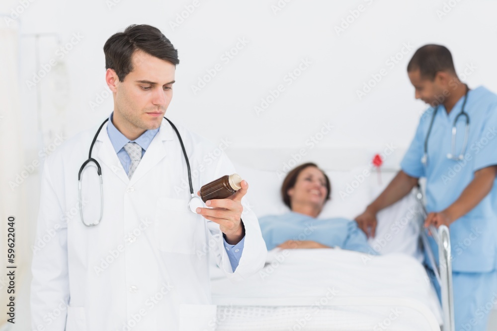Doctor holding a bottle of pills with patient in hospital Doctor holding a bottle of pills with patient in hospital