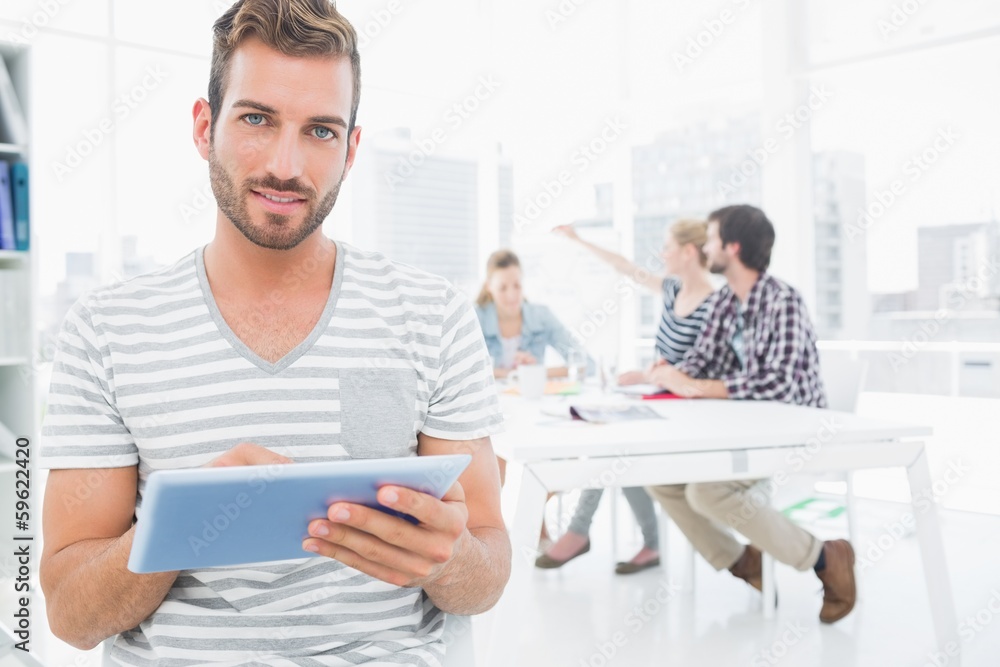 Fototapeta premium Man using digital tablet with colleagues in background