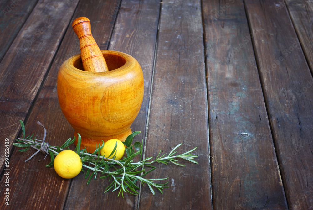 fresh rosemary herbs in wooden pestle and mortar on wooden table