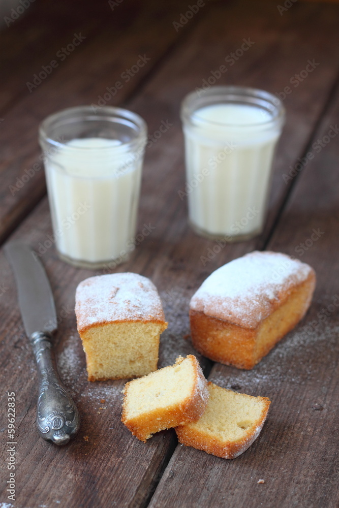 Small homemade muffins on a brown table with glasses of milk Small homemade muffins on a brown table with glasses of milk