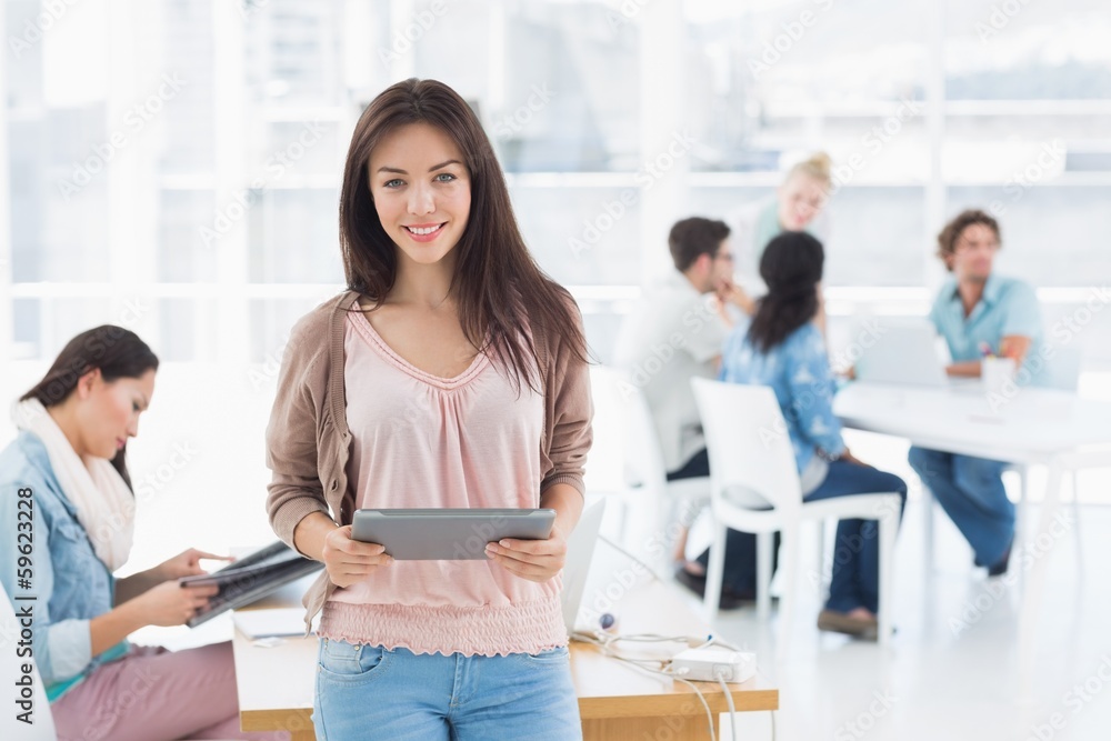 Artist holding digital tablet with colleagues in background at o