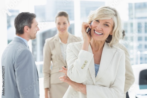 Mature businesswoman on call with colleagues at office