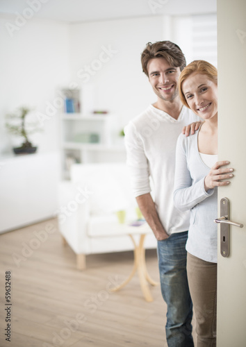 Cheerful couple inviting people to enter in home © jackfrog
