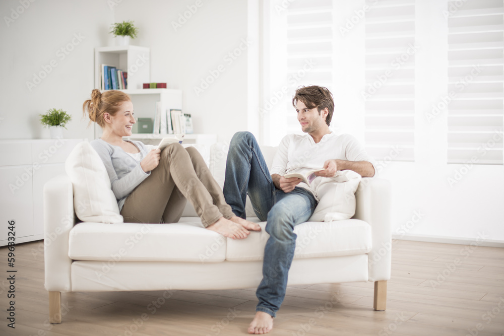 cheerful couple reading books on couch cheerful couple reading books on couch
